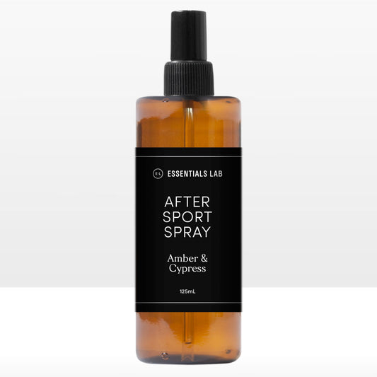 A clear amber spray bottle labeled 'AFTER SPORT SPRAY Amber & Cypress' on a white background.